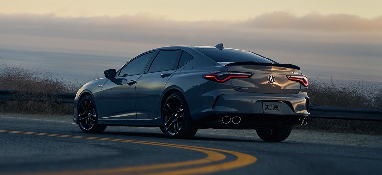 2026 Acura TLX with Technology Package in Liquid Carbon Metallic, rear view with a sunset in the background (Premium Sport Sedan). 2026 Acura TLX with Technology Package in Liquid Carbon Metallic, rear view with a sunset in the background (Premium Sport Sedan).