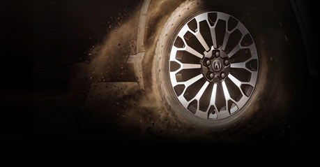 2027 Acura profile close up of a wheel spinning and kicking up dust on a dirt road.